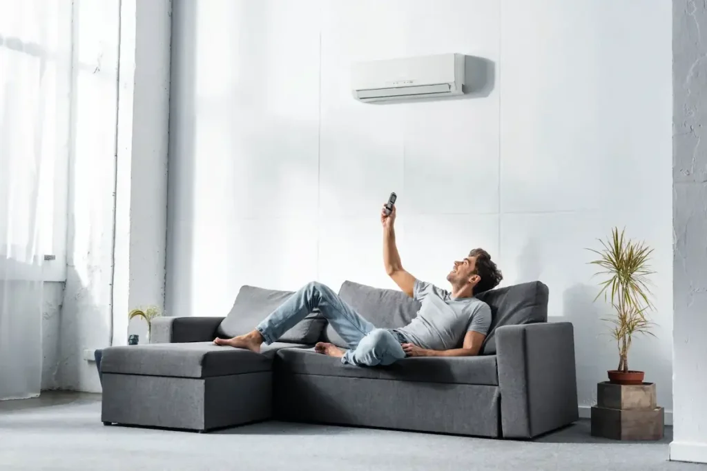 Man lying on sofa and switching on air condition